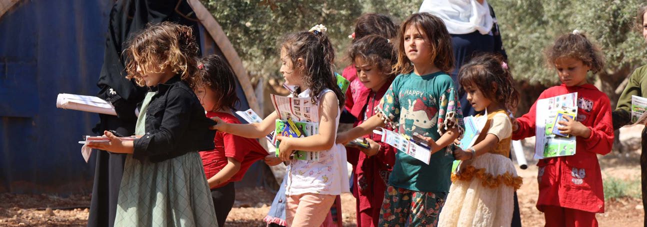 Children walk outside holding leaflets from their risk education session