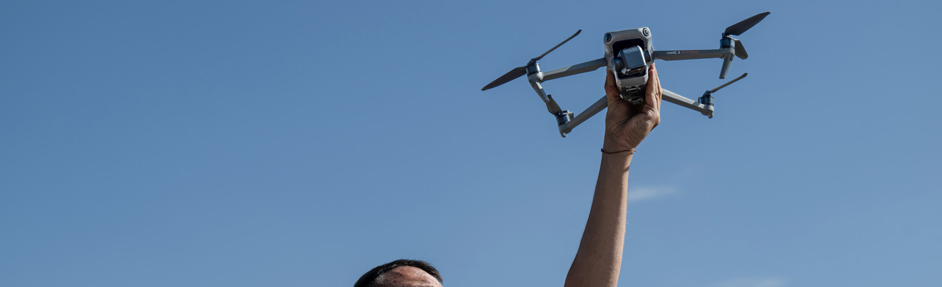 Рука тримає дрон на фоні блакитного неба