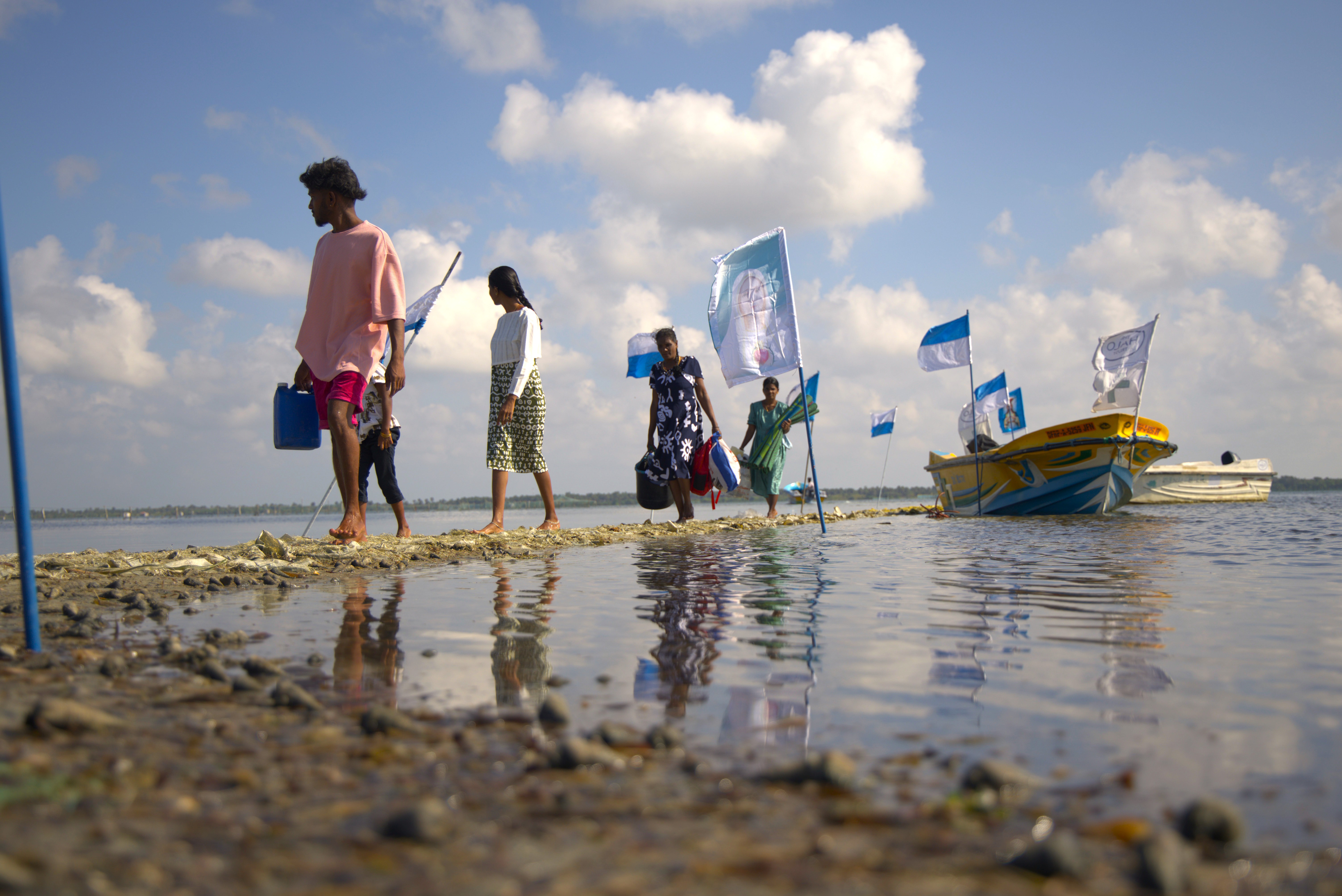 Parishioners walk on an isle of the lagoon away from their boat.