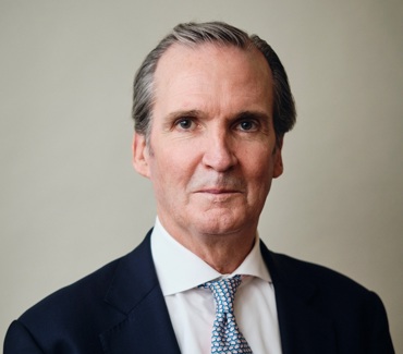 Headshot of Greg Swenson, who is wearing a suit and tie