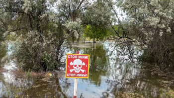 A red danger mines sign stands in front of the destruction of the Kakhovka Dam Flood