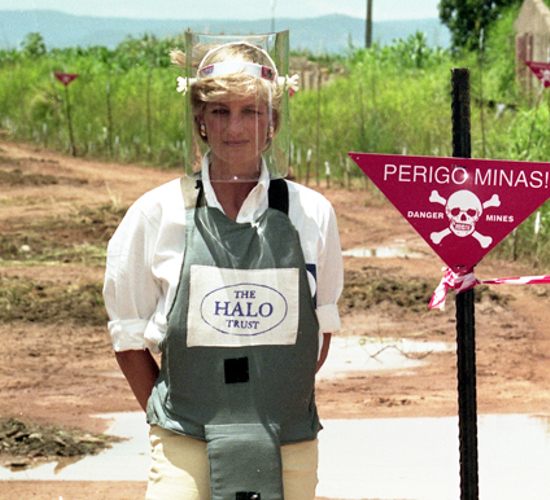 Princess Diana stands in front of a Danger Mines sign in a minefield in Angola