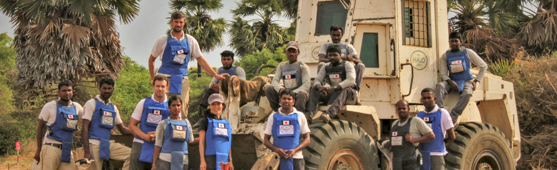Staff from the HALO Sri Lanka Programme stand next to a mechanical asset in PPE