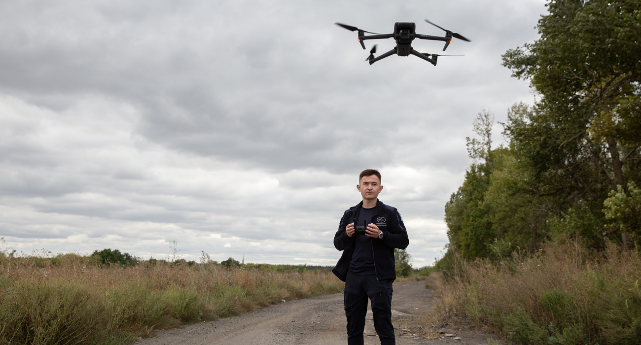Пілот дрону проводить розвідку щодо наявності мінної загрози в полях поблизу дороги