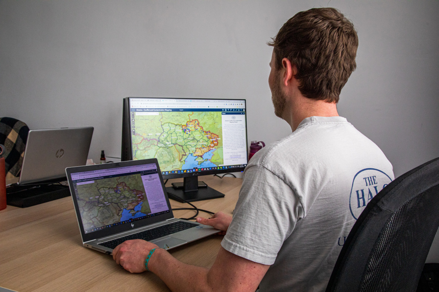 HALO staff member looking at 2 screens showing mine maps