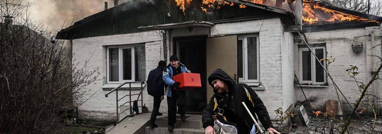Three people flee a burning house carrying their belongings