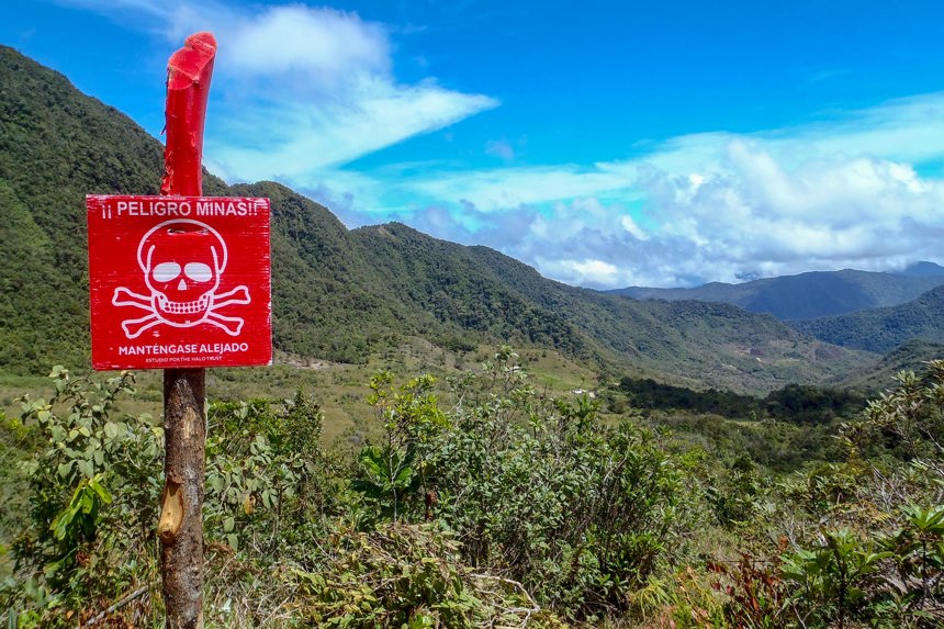 A red mine warning sign stands alone with a vast view of mountainous terrain in the background