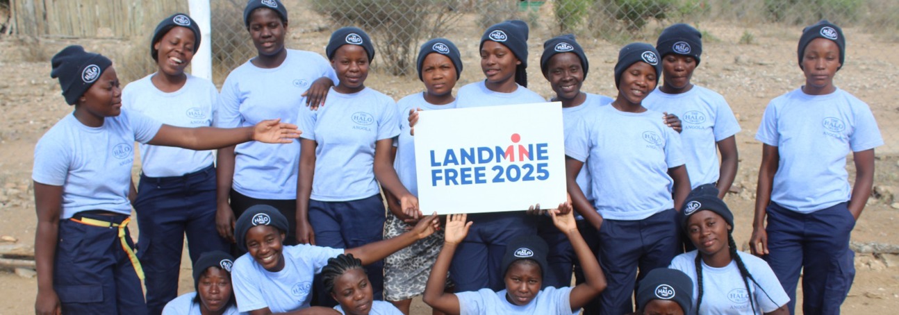 A female HALO demining team holding up a sign for a Landmine Free 2025