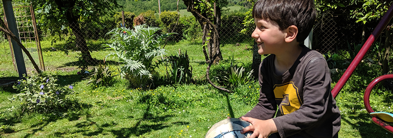 A boy sits on the grass in a garden in Primorsky