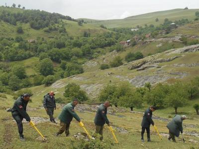 A group of HALO Trust staff use detectors to identify landmines on the side of a grassy hill in Nagorno Karabakh