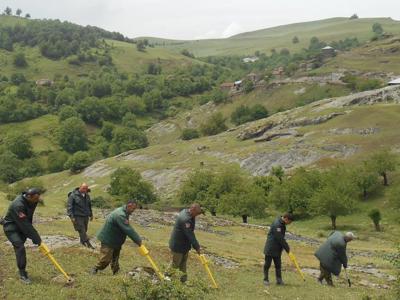 A group of HALO Trust staff use detectors to identify landmines on the side of a grassy hill in Nagorno Karabakh