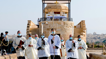 A procession of religious leaders walking through the epiphany site wearing face masks 