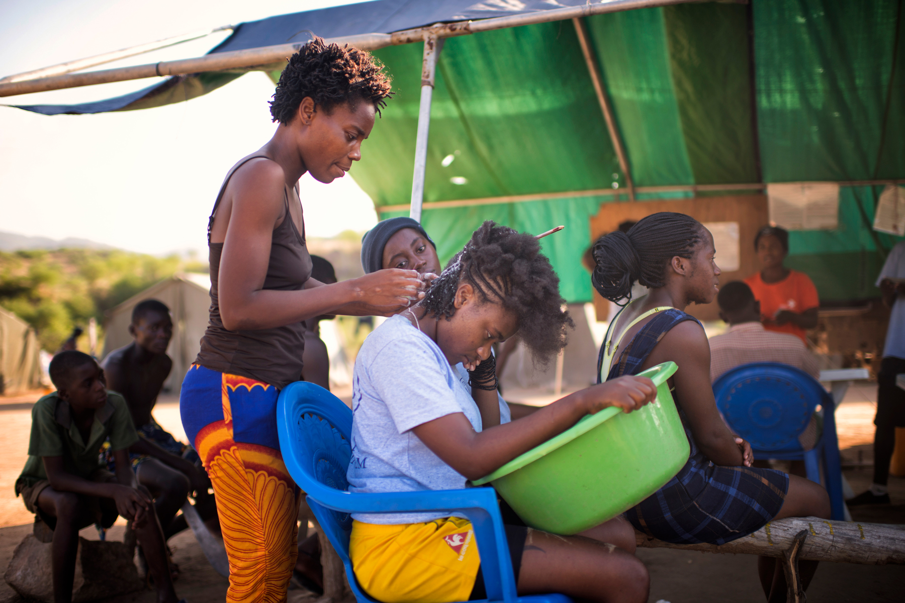 HALO deminers sit and braid each other's hair after work
