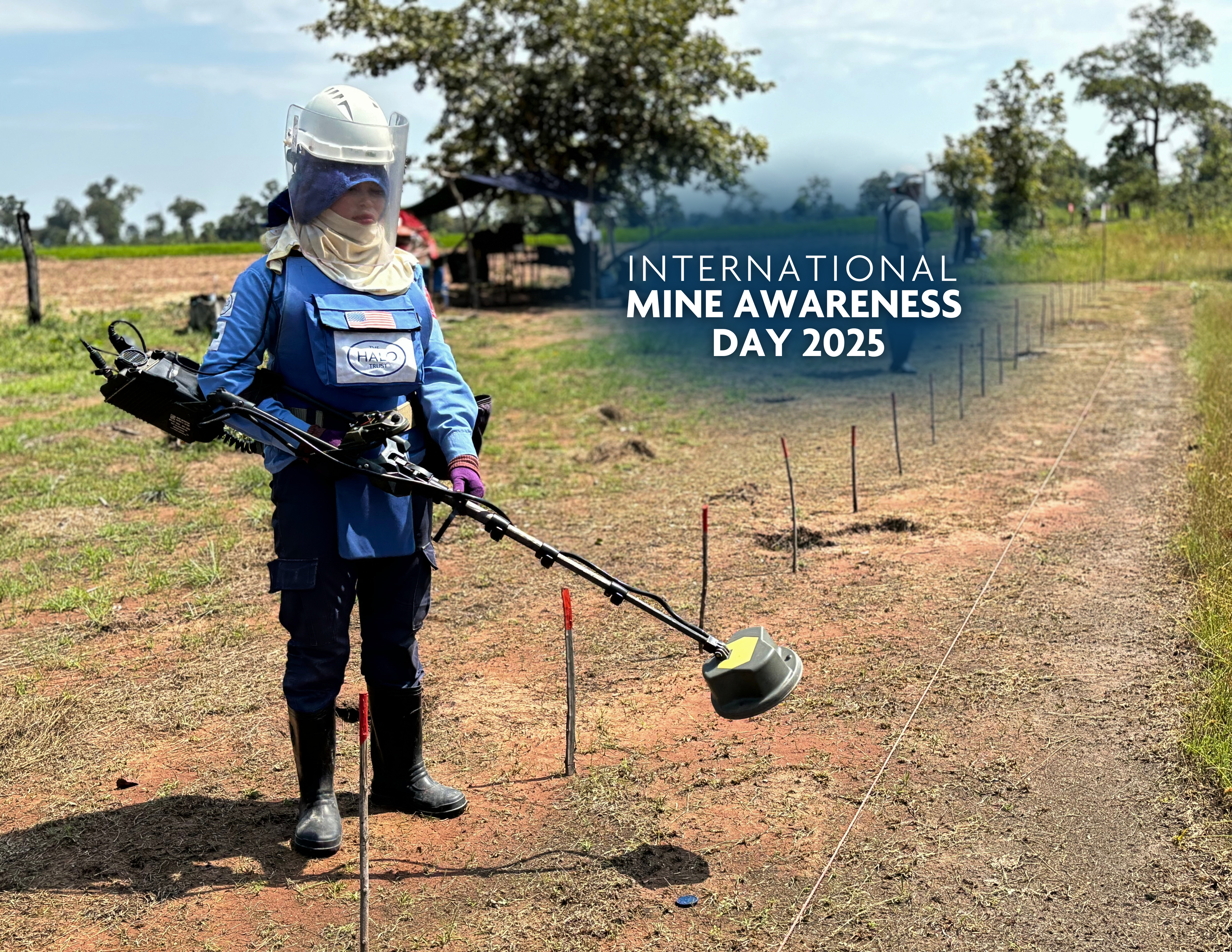 Deminer-wearing-PPE-stands-holding-metal-detector-marked mines