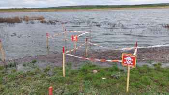Sticks in the ground fence of landmines and explosive contamination in a flooded field in Kherson Oblast, Ukraine