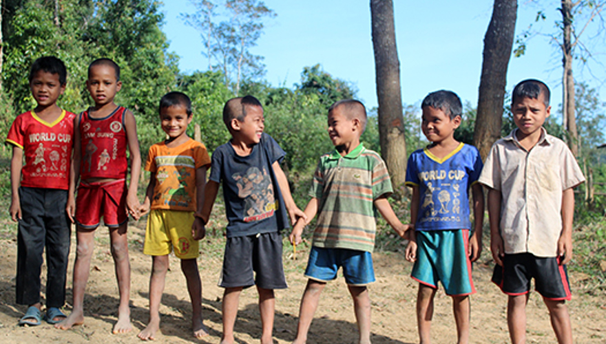 Kids smile together as they pose in a line outside