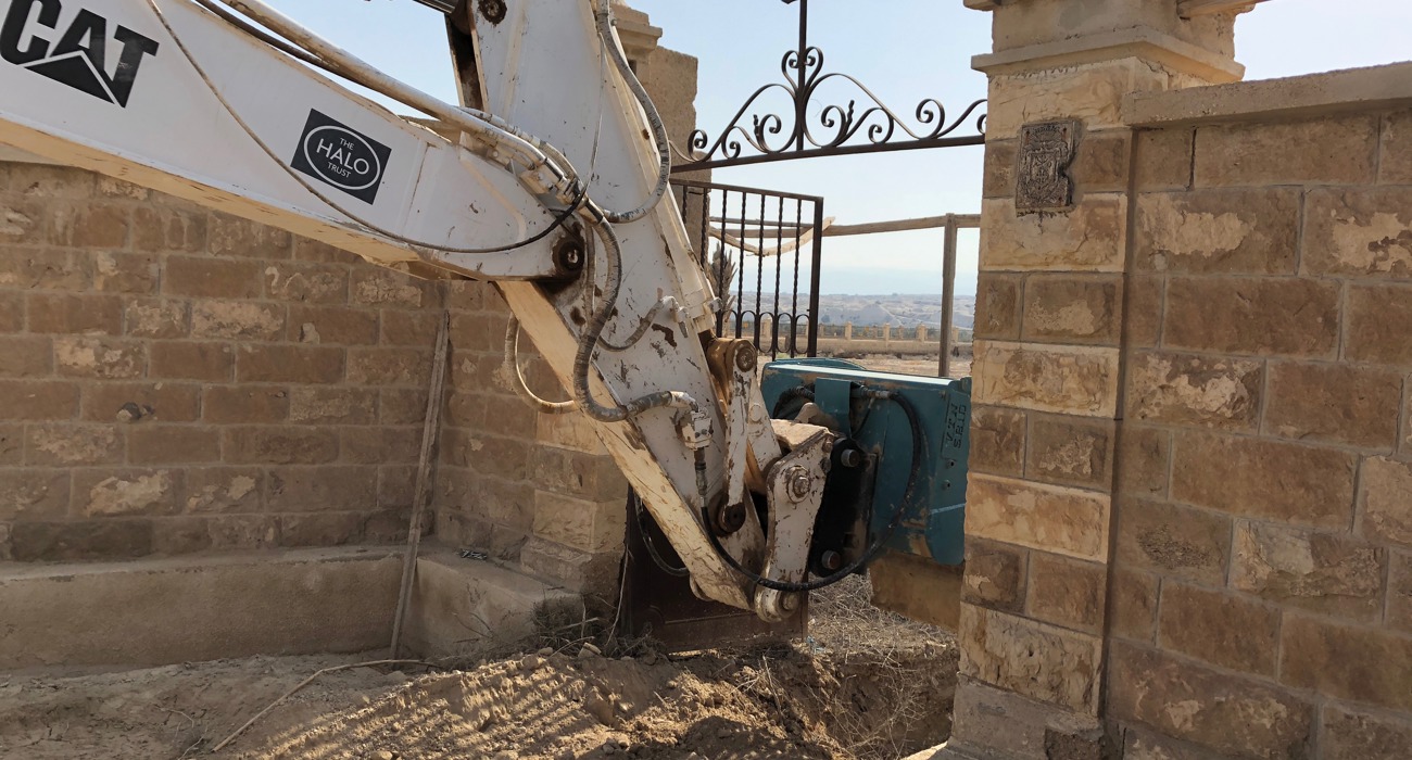 An armoured digger removes explosives by the gate of the Franciscan Compound