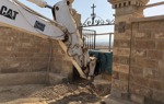 An armoured digger removes explosives by the gate of the Franciscan Compound