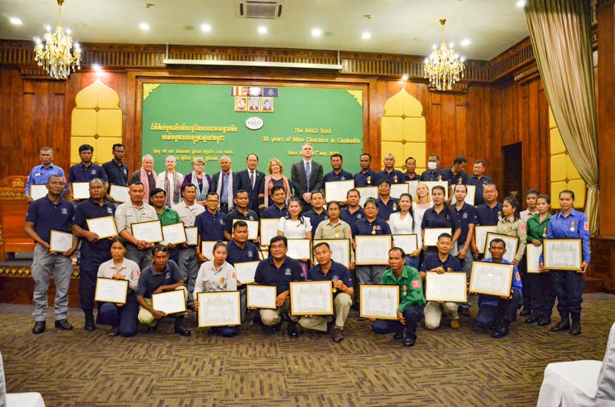 A large group of HALO Trust staff holding certificates in a decorated hall