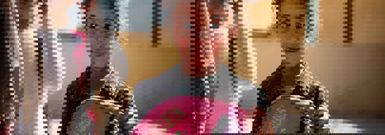 Syrian girl holding a backpack and smiling