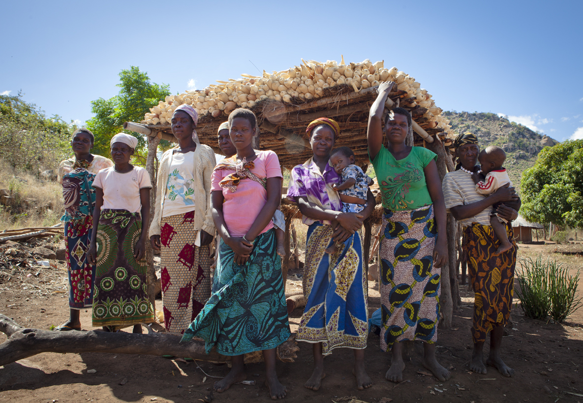 Group of women standing together in front of their maize harvest in Mozambique
