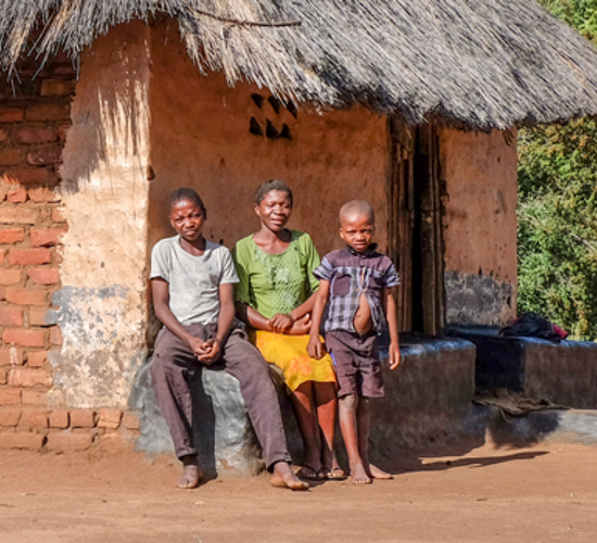 Sadzuri Kamoyo sits on a wall with two sons