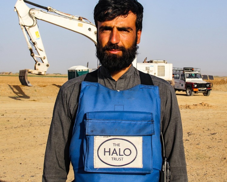 Sayed Maqsood Hashimi, a team leader in Afghanistan, stands in front of a digger in a minefield in Afghanistan