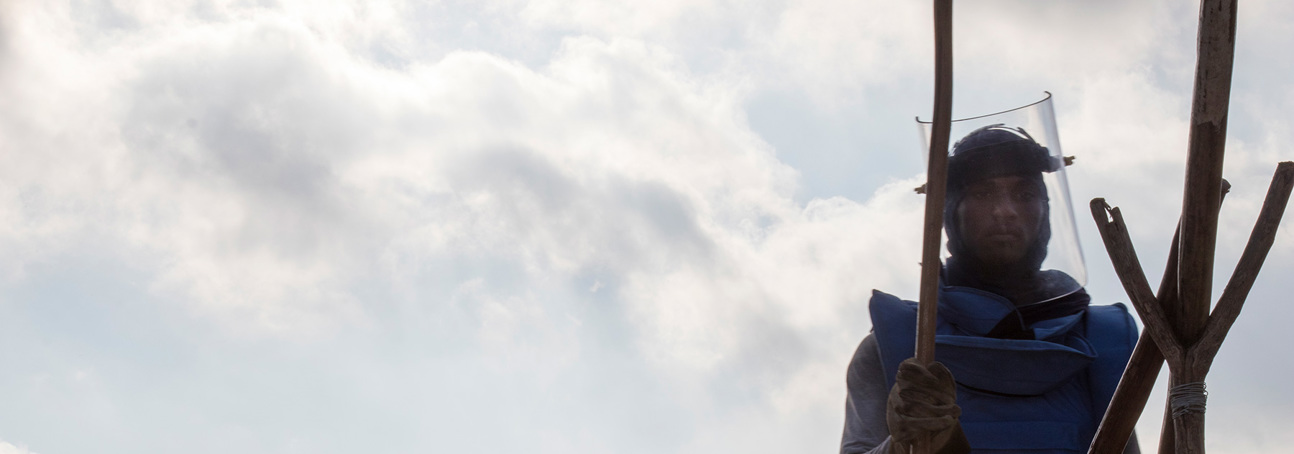 A HALO deminer in Sri Lanka stands in PPE displaying the US flag while wearing a visor
