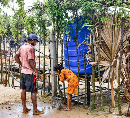A man and child get water from a water tank outside
