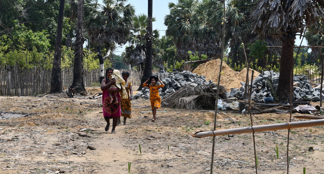 Two women, a young girl, and a toddler walk away from a pile of rocks.