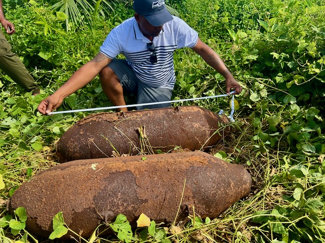 A man measures two large aircraft bombs
