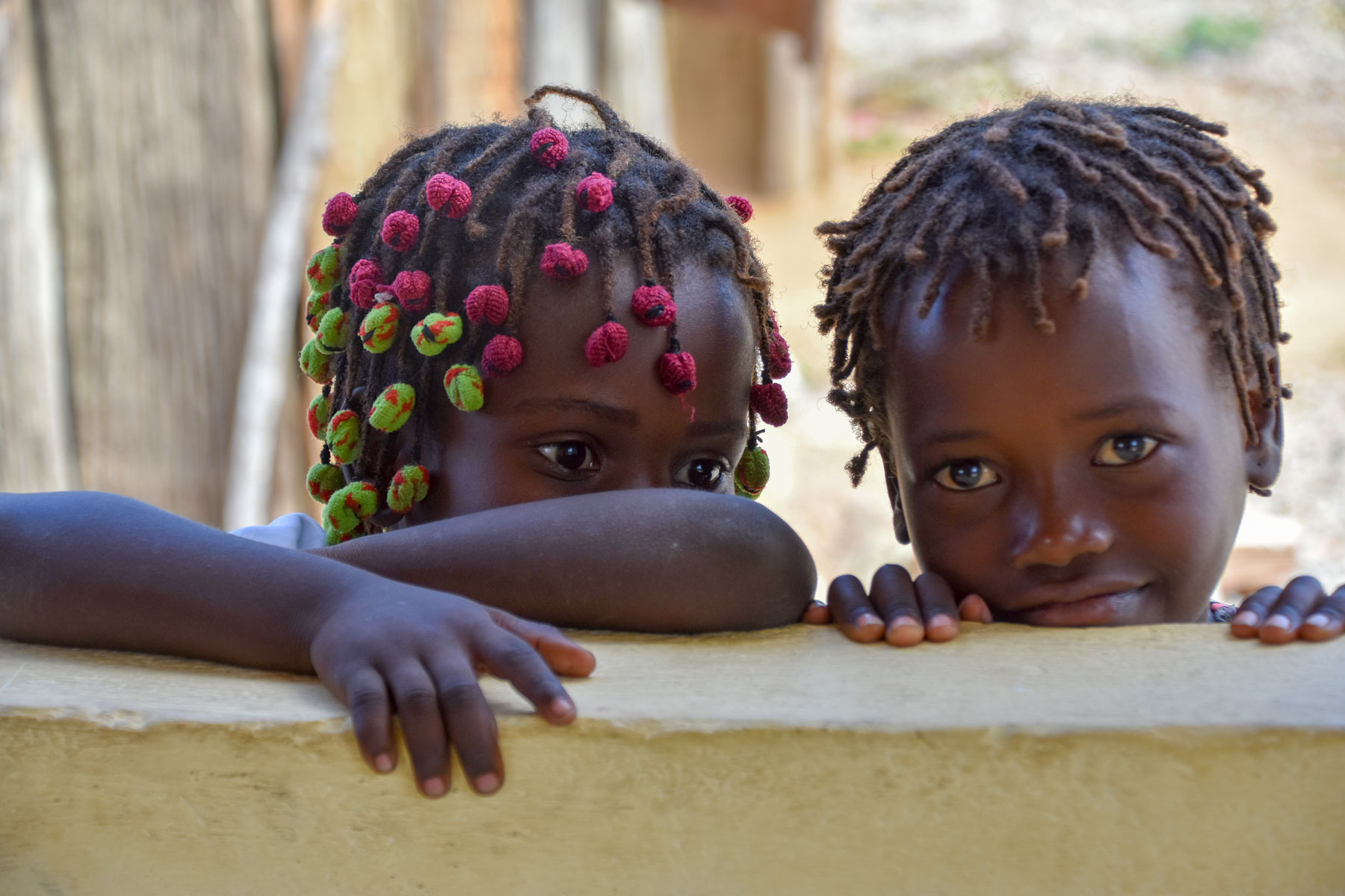 Two children lean on a wall of a school in Angola