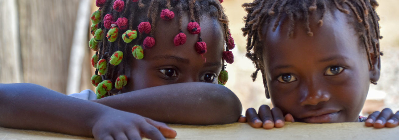 Two children lean on a wall of a school in Angola
