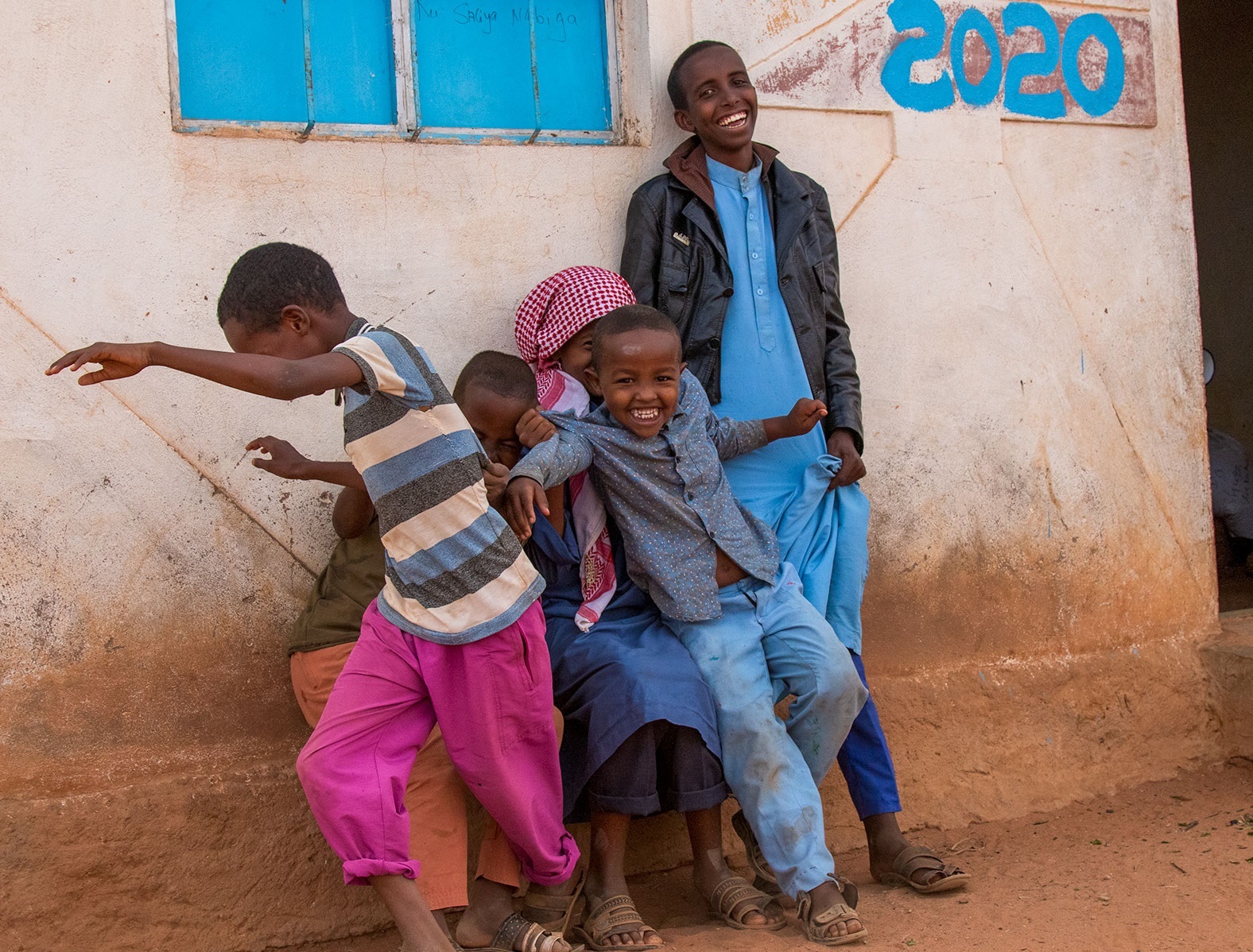 Children laughing against a wall in Somaliland.