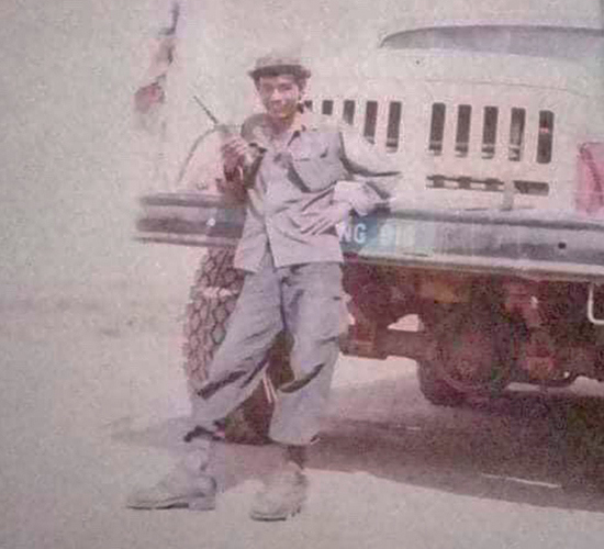 Mr Ream Sarath stands in front of a large vehicle wearing HALO Uniform and holding a radio