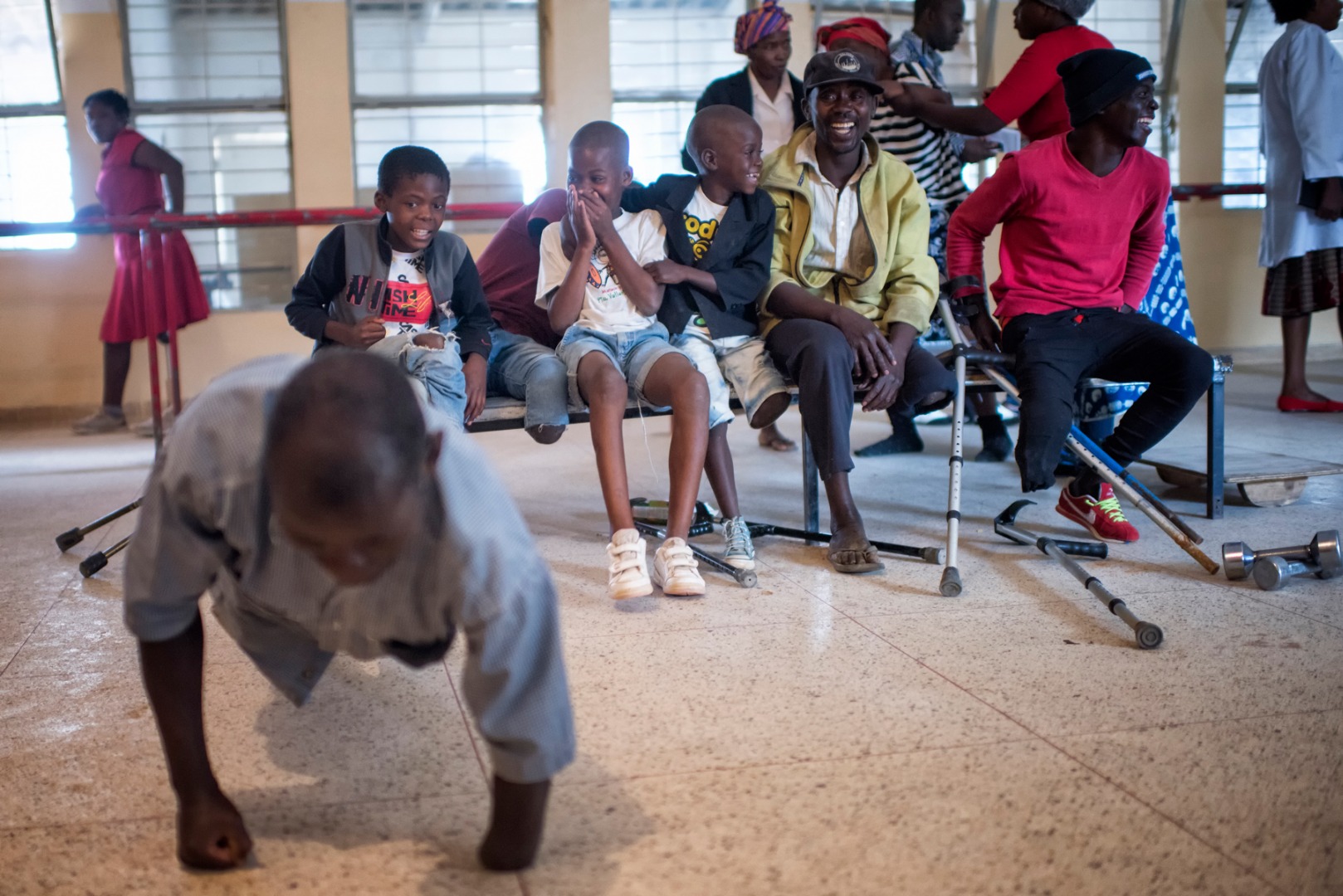 A man does push-ups on the floor in front of children at the rehabilitation centre