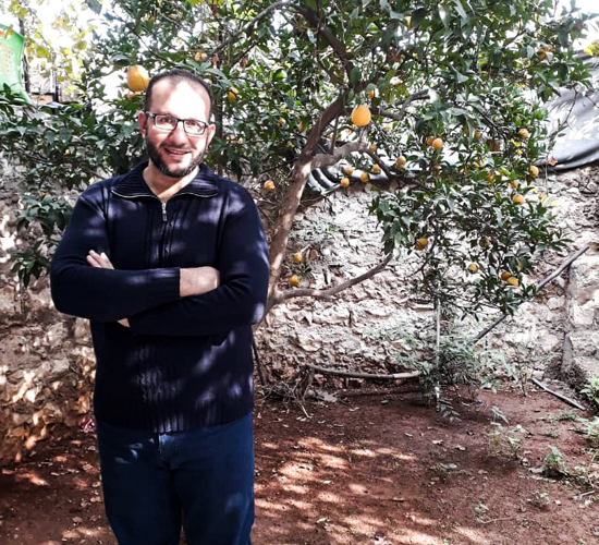 Sa'eed stands next to a lemon tree in Syria