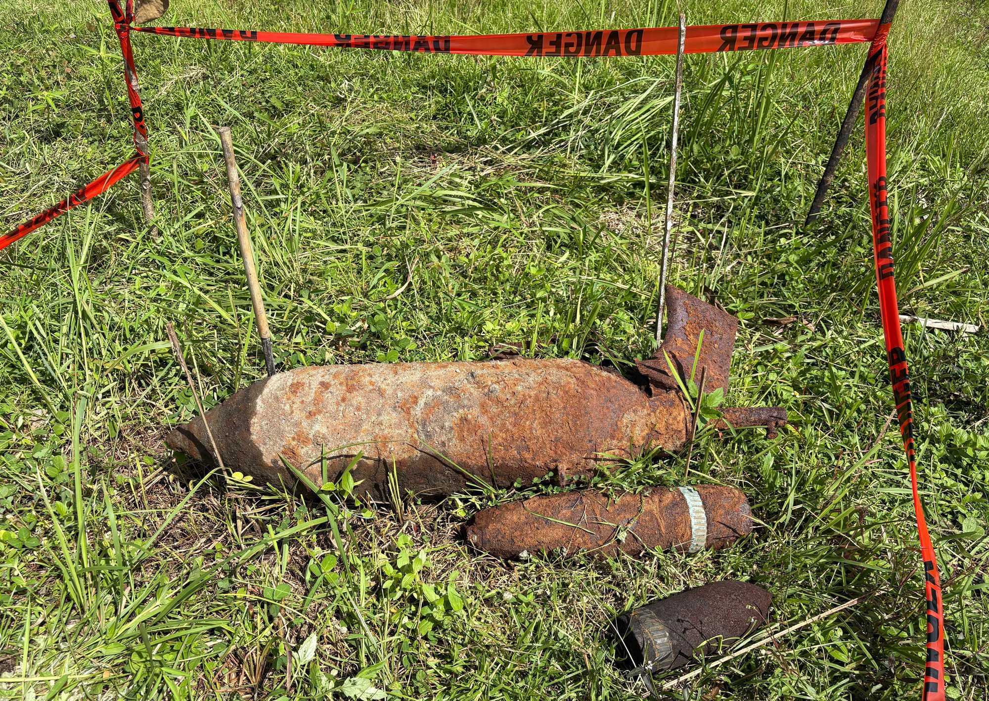 Rusted UXO found outside of a schoolhouse marked by red tape for safety