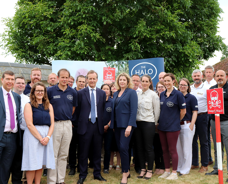 Former Secretary of State for International Development, Penny Mordaunt, stands with HALO  staff in front of a HALO banner