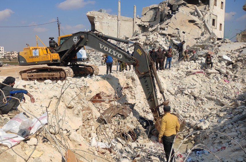 A digger clearing rubble in a community in Syria