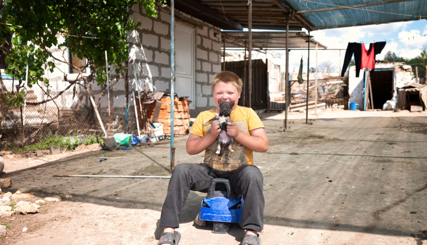 Син Володимира та Юлії грається з цуценям та машинкою на подвір'ї