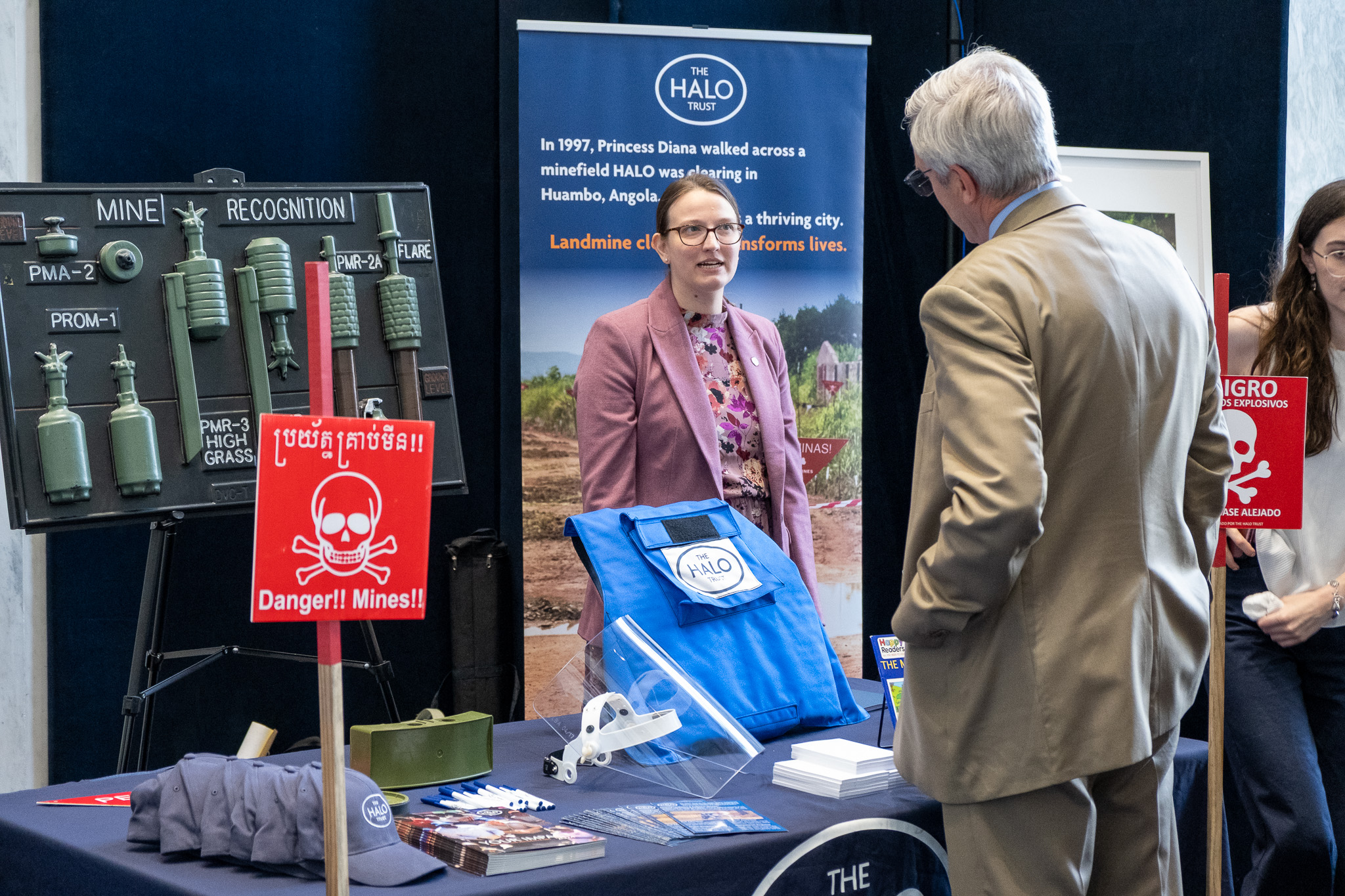 Kristen. a HALO staff member, speaks to a visitor at HALO's Mine Awareness Day table.