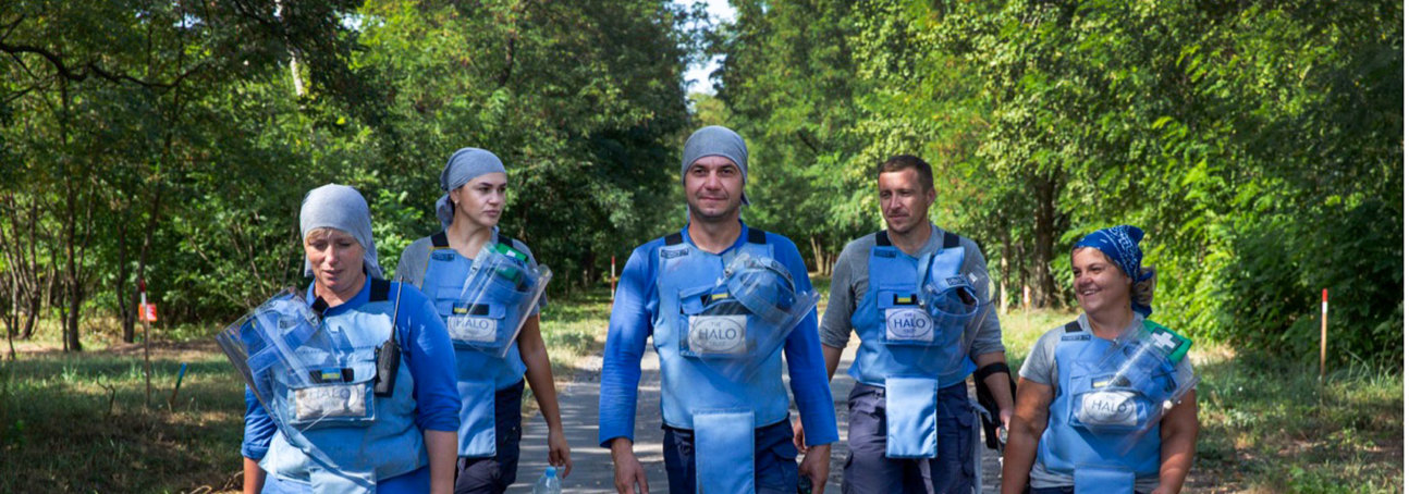 A team of HALO Trust deminers walk down a road in PPE in Ukraine