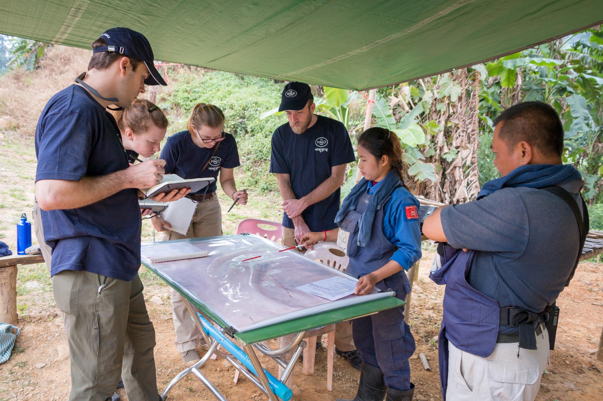 Acting Field Officer Pat Liav briefs new trainees at a minefield in Pailin while Location Manager Ming Ty looks on. 