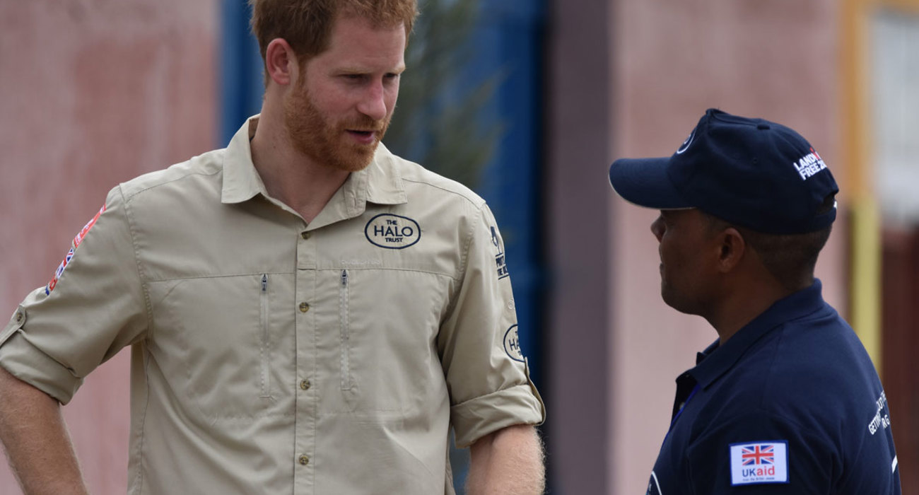 Prince Harry talks with a HALO Trust staff member wearing a HALO Trust shirt in Huambo, Angola