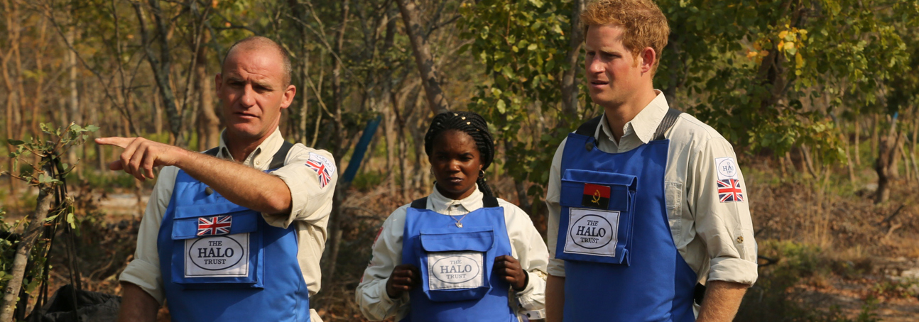 Prince Harry stands with a team of HALO deminers while wearing PPE