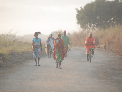 Women in colourful clothes walk along a dirt road in Mozambique