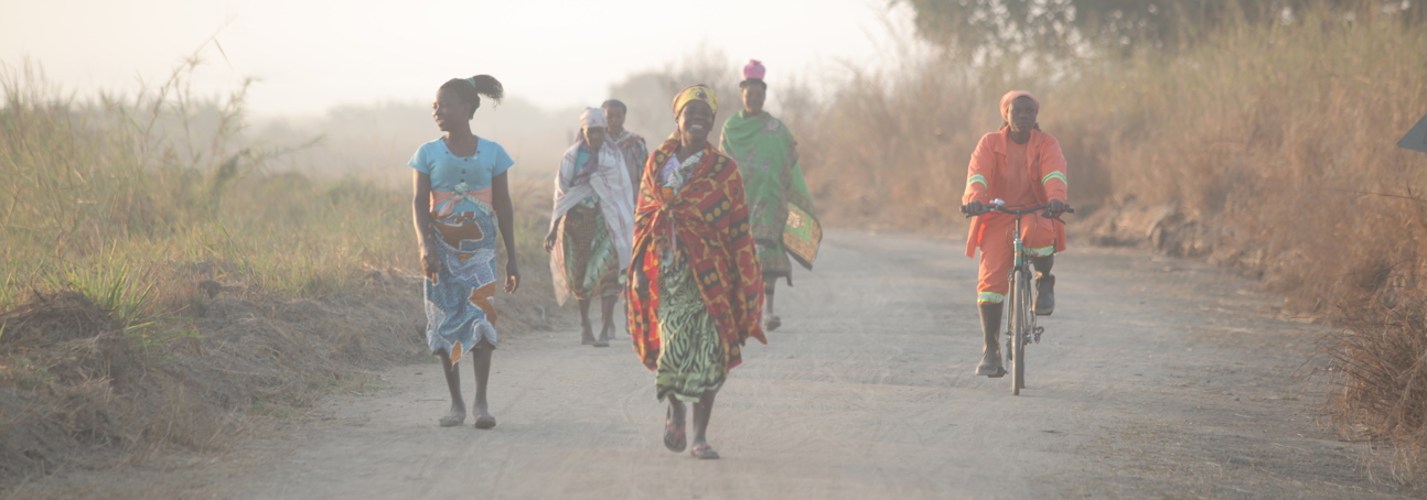 Women in colourful clothes walk along a dirt road in Mozambique