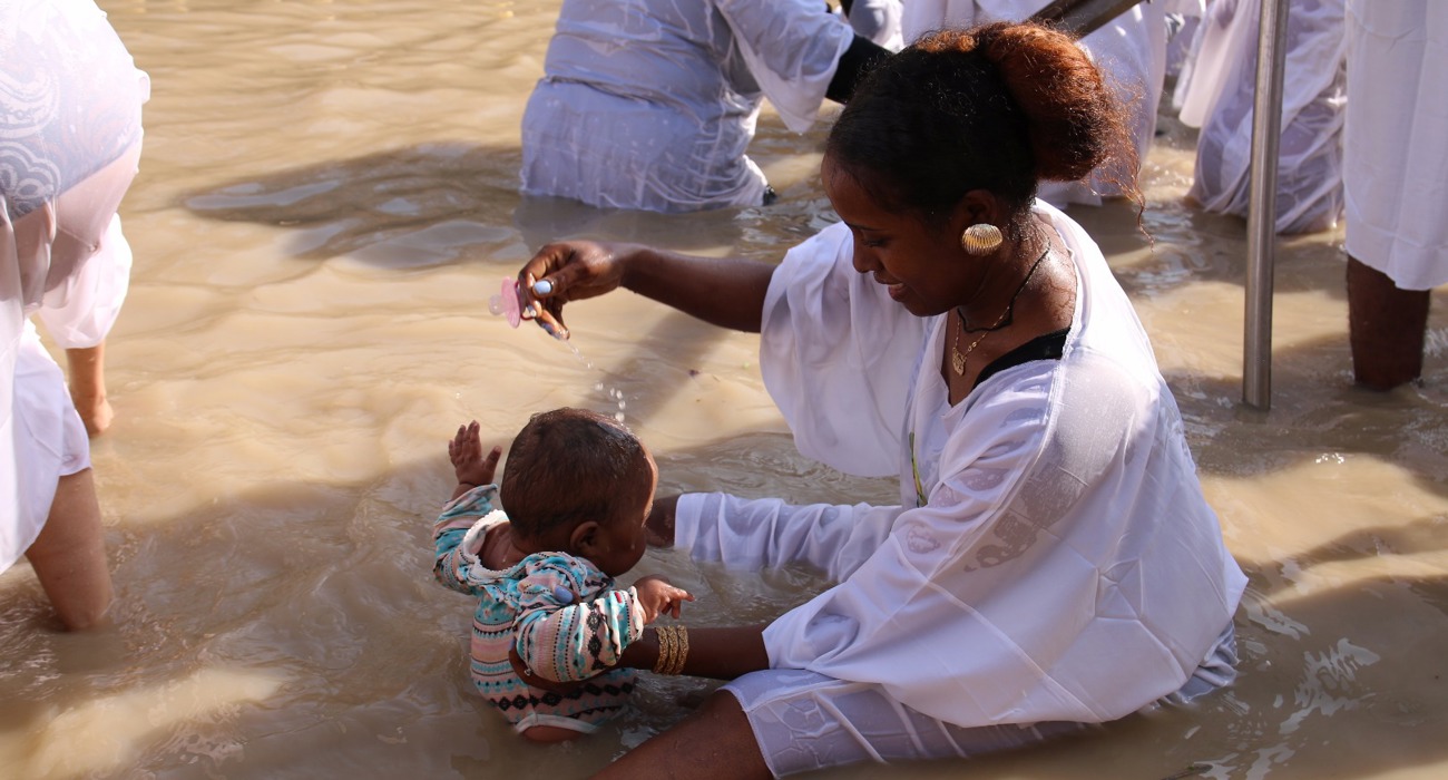 A child is baptised during the Epiphany celebrations in the Jordan River