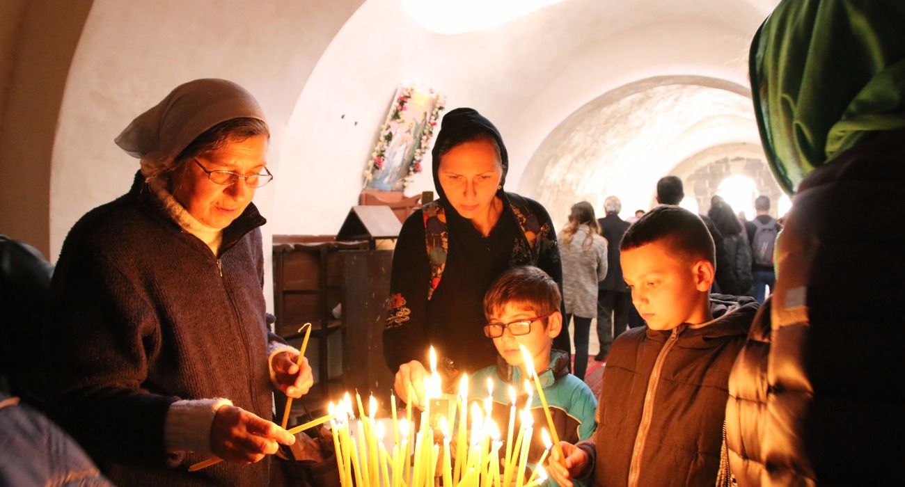 Children and adults gather to light candles at the Baptism Site